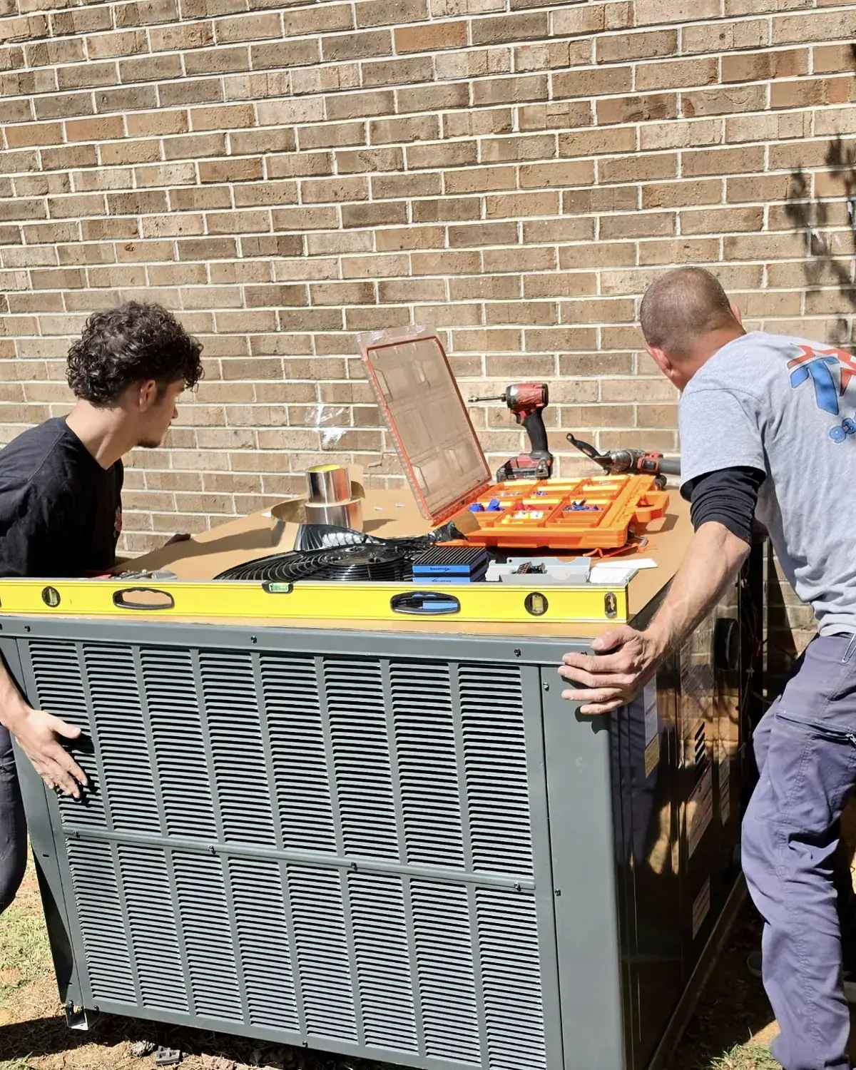 Two Tramont technicians carrying a new condenser