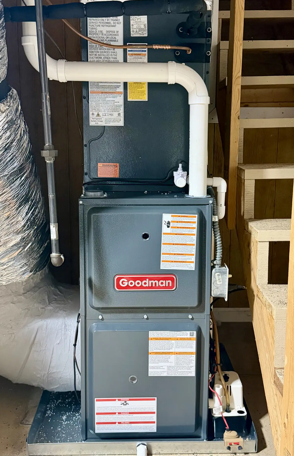 Goodman gas furnace and coil installed beside a basement staircase