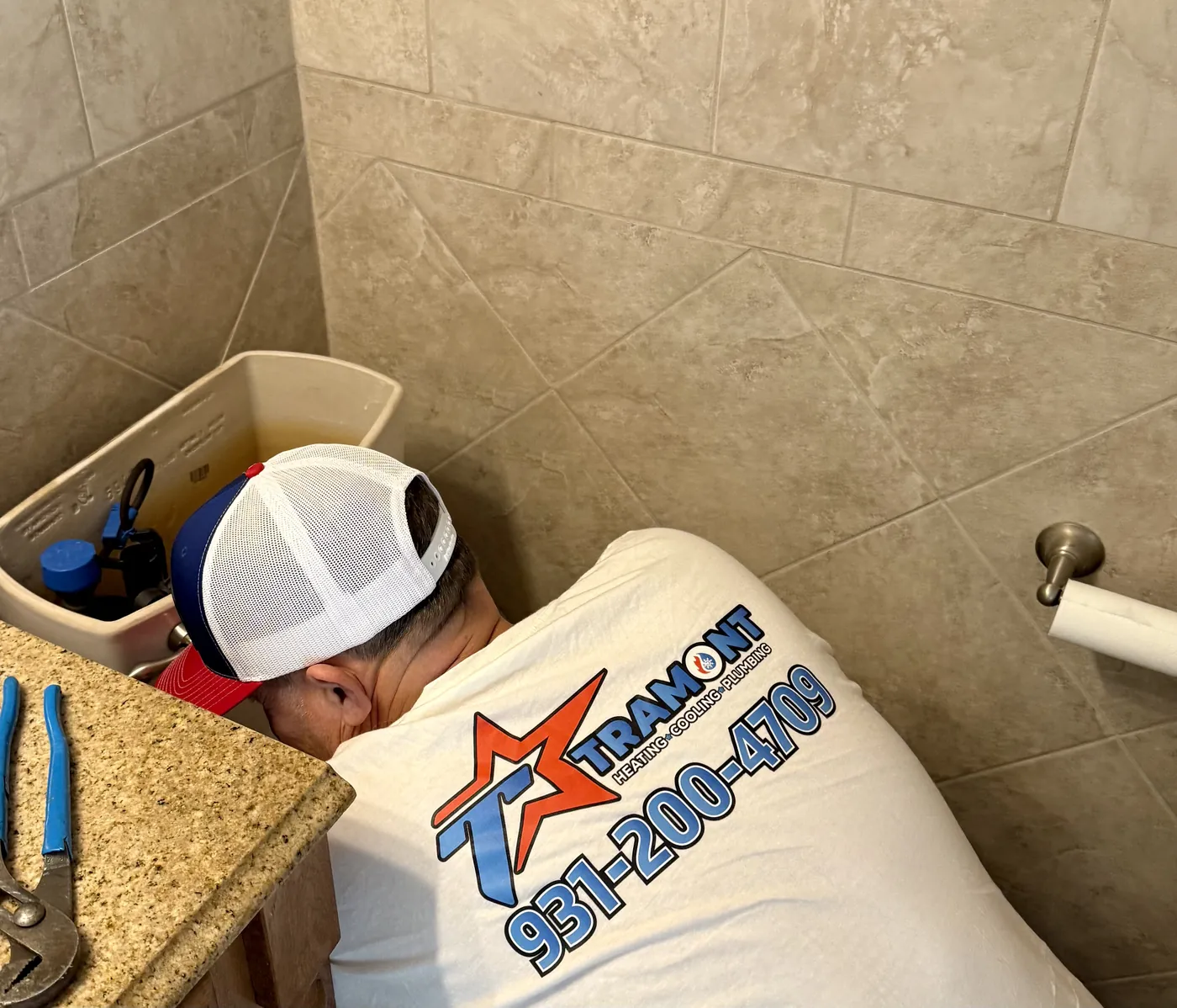 Tramont plumber working on the pipes under a bathroom sink