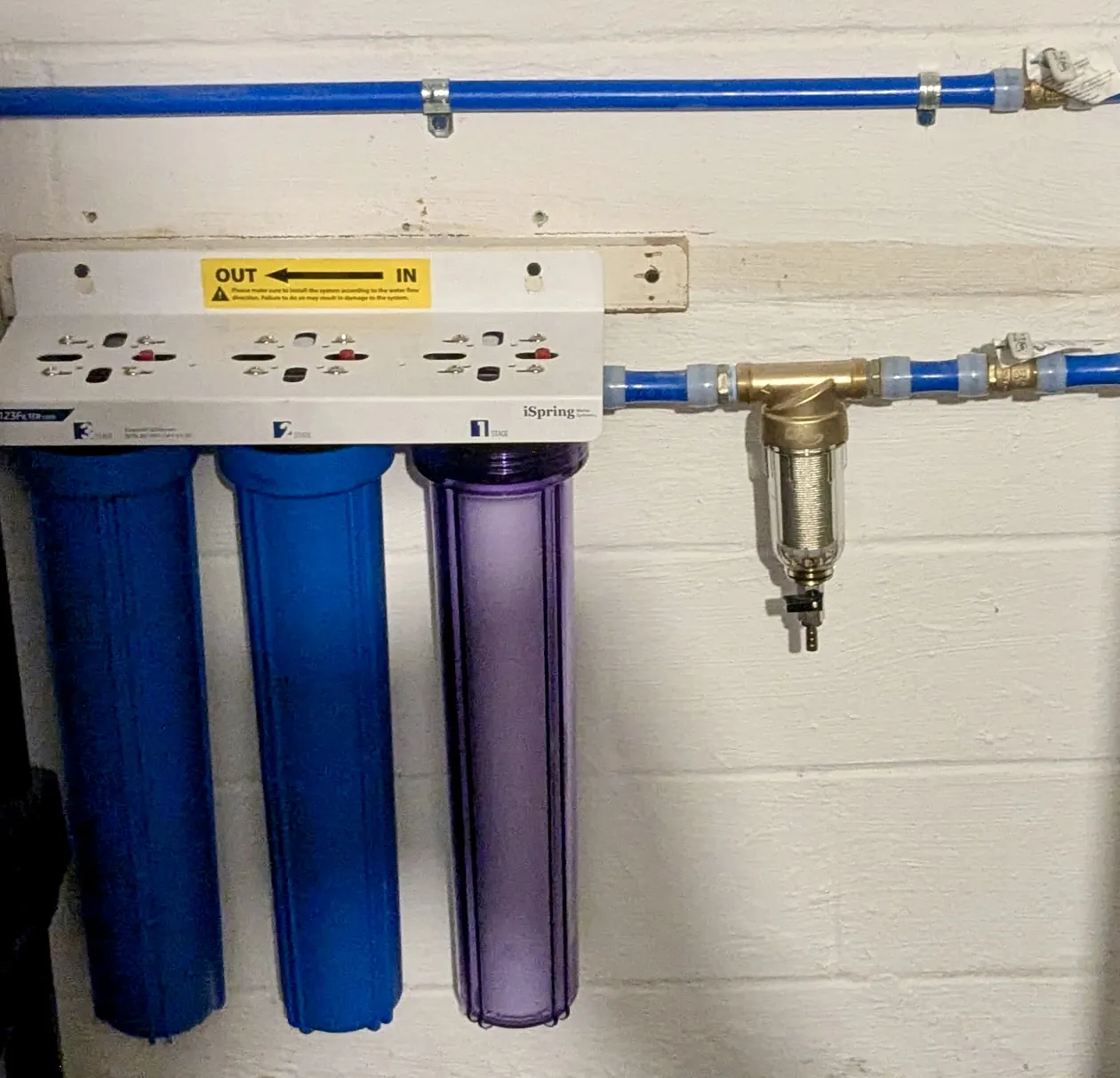 Whole-home water filter housings on a basement wall