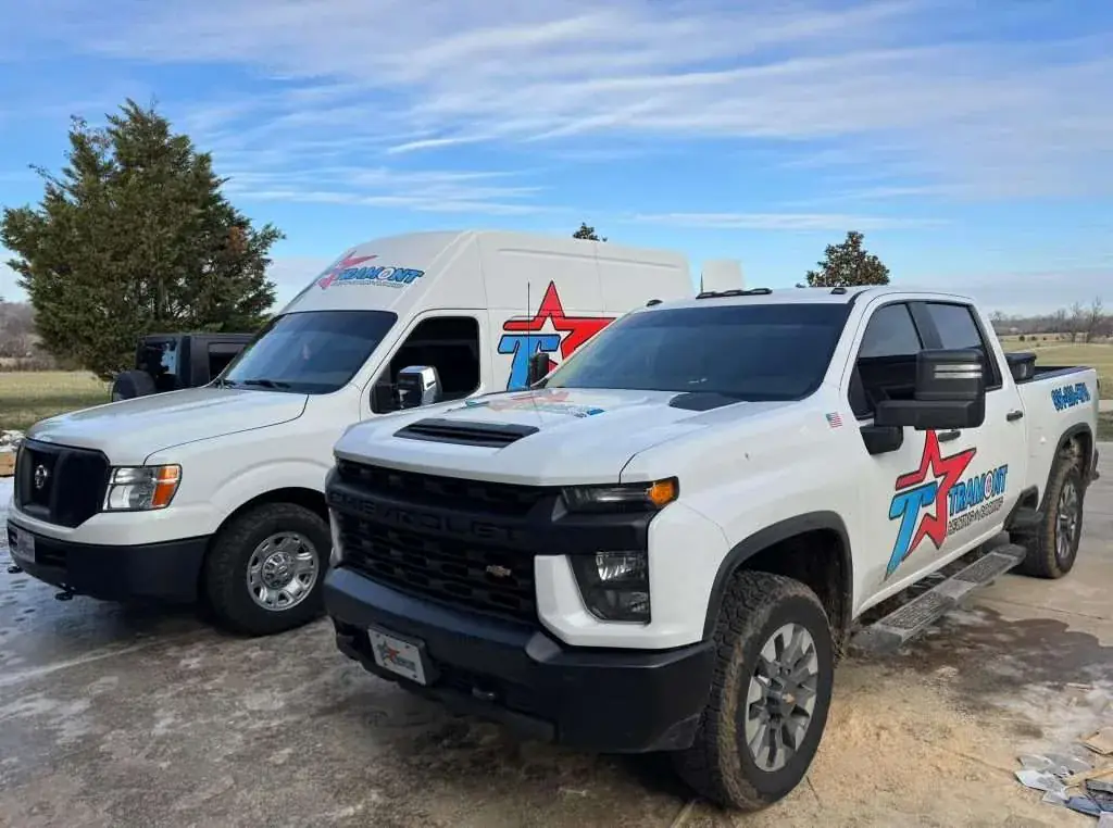 Two Tramont Heating Cooling Plumbing service vehicles parked outside a home