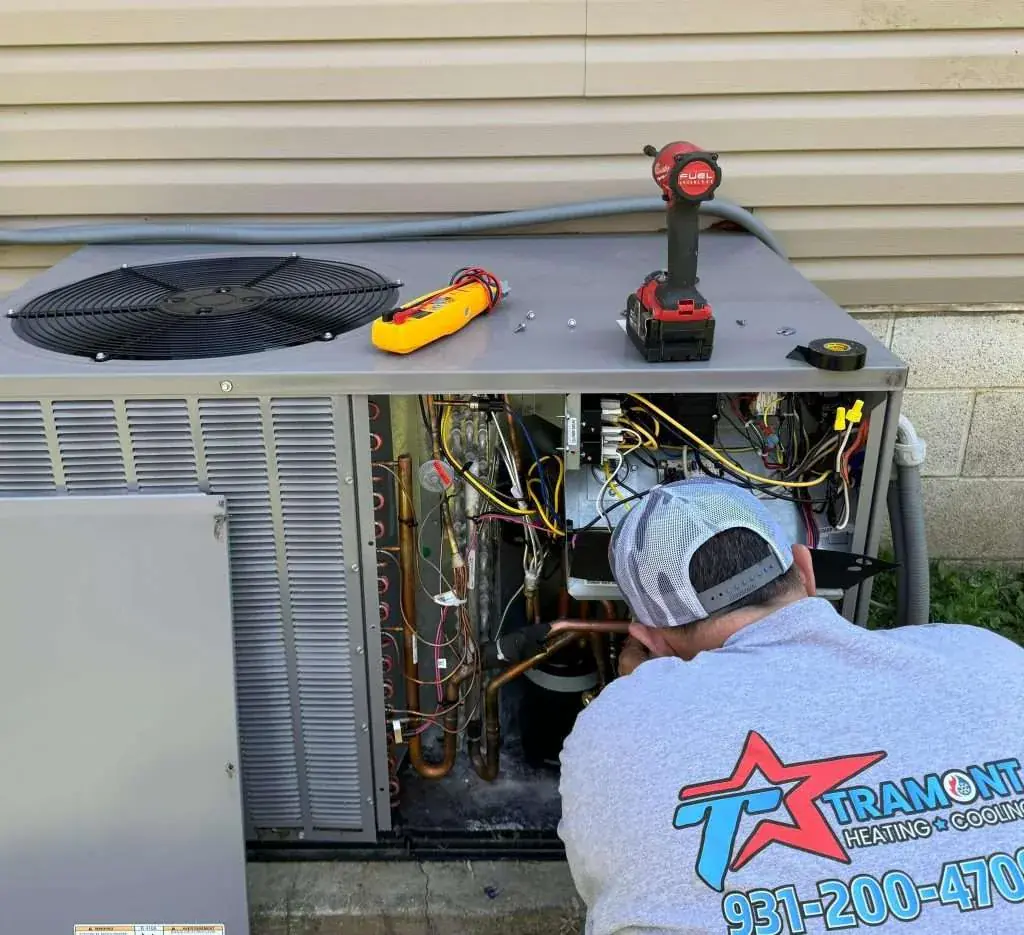 Tramont technician performing AC repair surrounded by tools